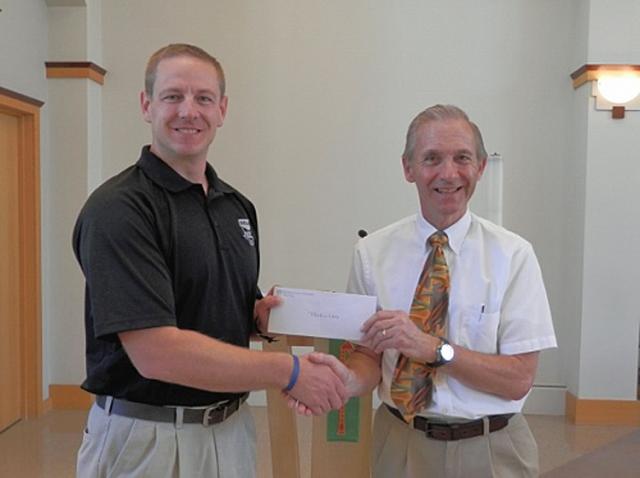 George Bauer, President of the Congregation, presents Lt. Eric Dickinson of the Vinton PD a check.