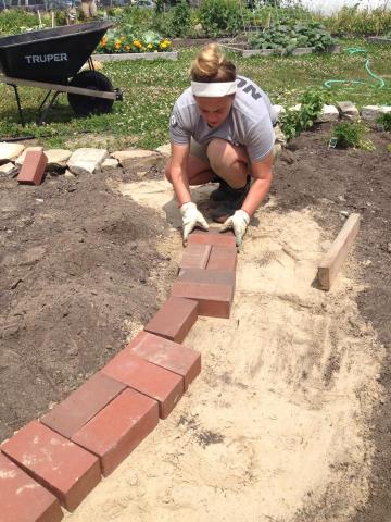 Cedar 3 member Emily builds a brick path for the herb garden at Toledo GROWS
