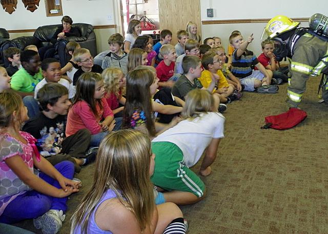 Firefighter Luke Henkle shows second graders what a firemen looks like when he enters a room.