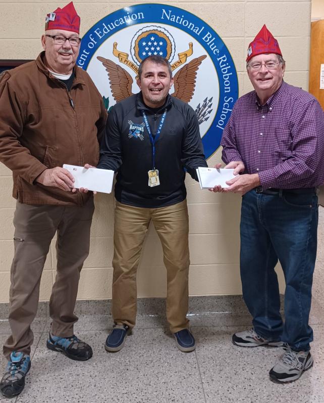 Roger Uthoff (Commissaire Intendent) and Alan Woodhouse (Chef-De-Gare) present Tony Islas (Assistant Principal) with gift cards for the Backpack Program