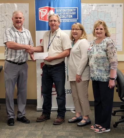 Matthew Werner presents a check for $2300 to Scott Hansen, Co-chair of the Benton County Disaster Recovery Coalition. Also representing the Coalition are Linda Fischer, Public Information Officer, and Tina Eden, Secretary.