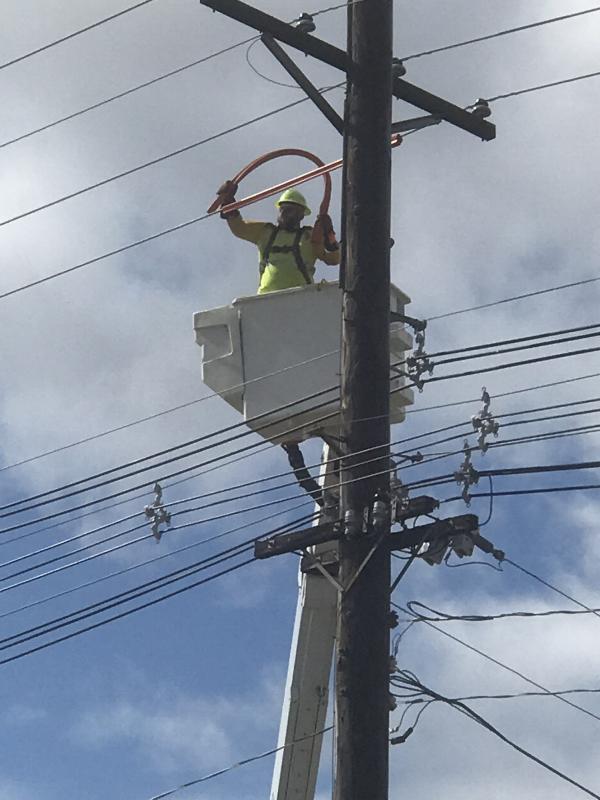 Article Thumbnail. Placing a tube over the powerlines to protect the worker