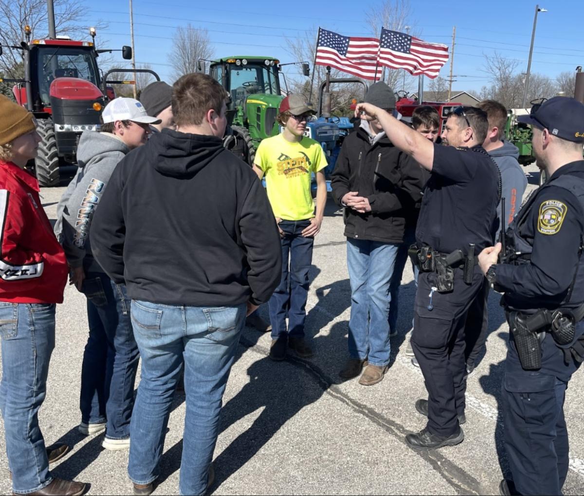 Officer Josh West gives students careful instructions to keep everyone safe before the tractors drive through town.. Click to read article