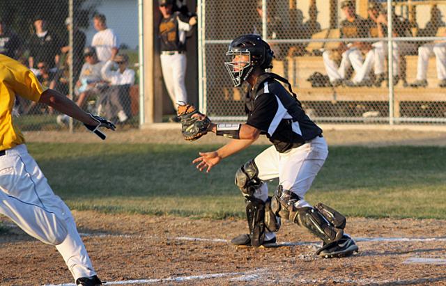 Aaron Henderson awaits a throw at the plate; the Benton runner scored on the play.