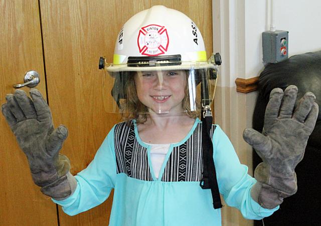 Addyson Chvala tries on a firefighter's gloves & helmet Tuesday during a visit to the fire station.
