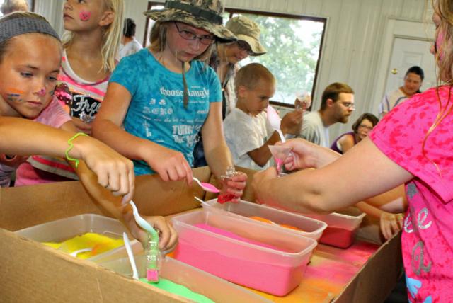 Children fill decorative bottles with colored sand.