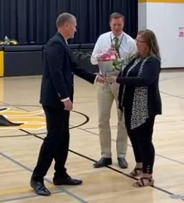 School Board President Tom Burke presents Middle School Principal Shelly Petersen with a bouquet in congratulations.