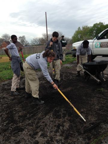 Cedar 3 shoveling compost to fill new raised beds that were installed by previous volunteers