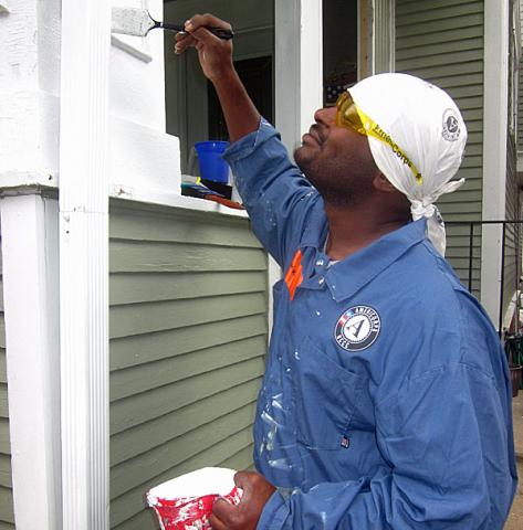 Bakari paints the frame of a home in Cedar Rapids.