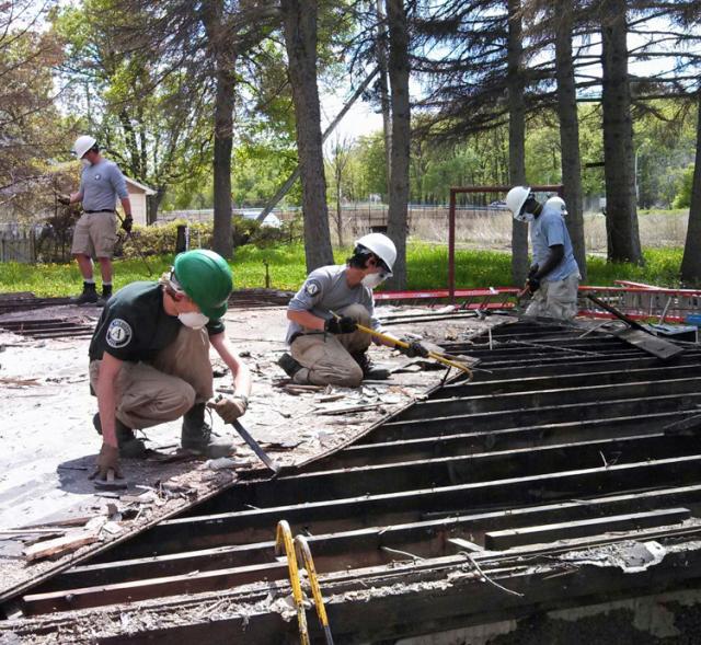 Lexus Hunt, Nick Rossmiller, Jerry Kim, and Gilbert Howard remove the subfloor from a house.