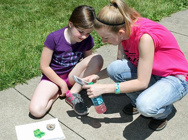 Sarah Kirschbaum helps a student take photos of her two types of wasp nests during Discovery Camp.