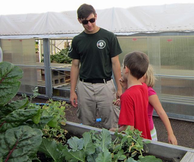 NCCC Cedar 4 Team Leader Joe is educating the two campers about vegetables growing in the bin.