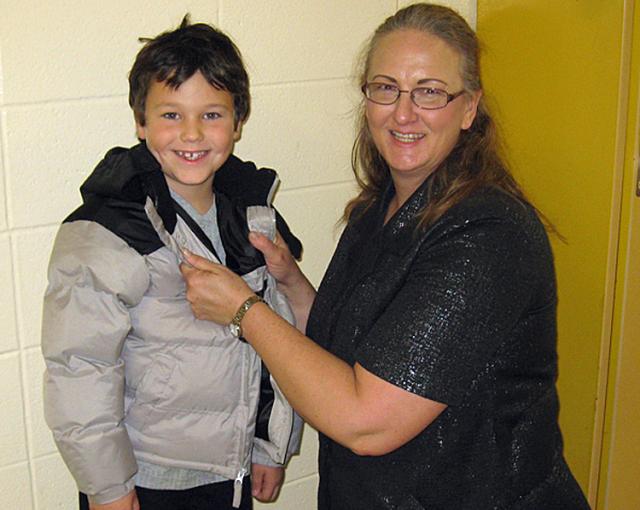 Guidance counselor Sharla Wrage helps put a coat on Chris Dague, 1st grader.