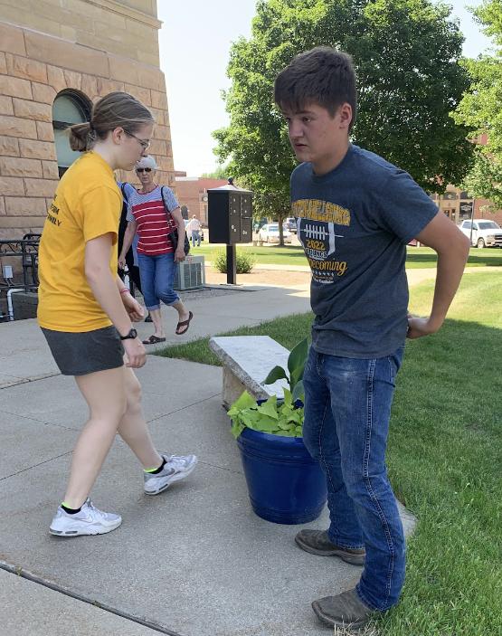 Rachel Rollinger and Ben Buhr placing flower pots in front of the Benton County Courthouse.