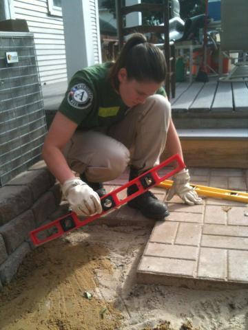 NCCC FEMA Corps Team Leader, Ashley Merchant, scales the brick tile to make sure it is even.