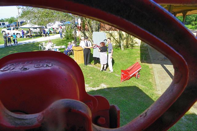 The unveiling of the sign, as seen through the wheel of the caboose.