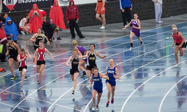 In the rain: Erika Hammar passes the baton to Shelby Beyer, who anchored the 4 x 100 team.