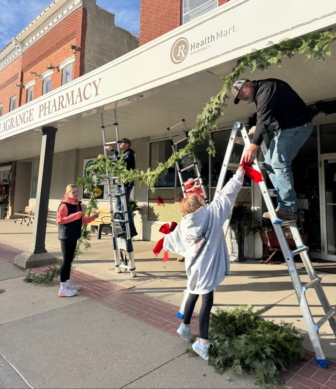 Katie Birker, Cole Birker, Lily Kakac, and Scott Birker hanging garland downtown. . Click to read article