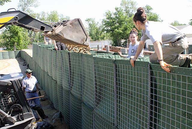 AmeriCorps members help with the second layer of Hesco flood barriers Friday morning.