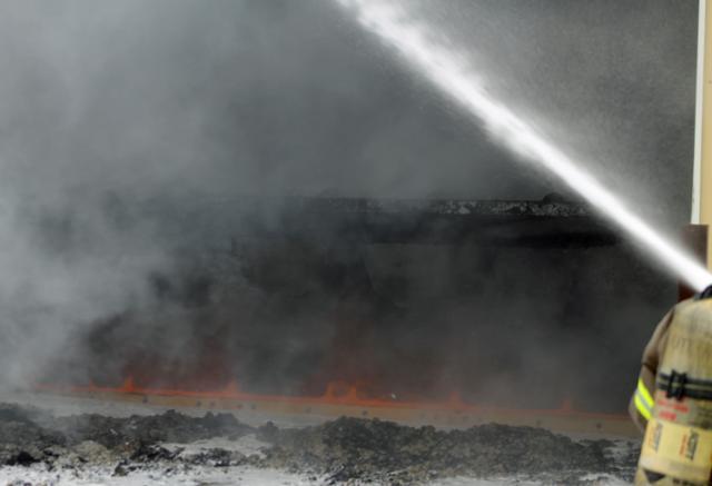 A destroyed county road maintenance truck is barely visible during Saturday's fire.