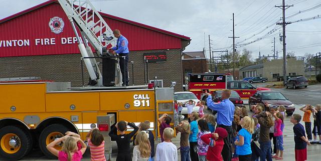 Second grade students watch as Luke Henkle demonstrates the aerial ladder truck.