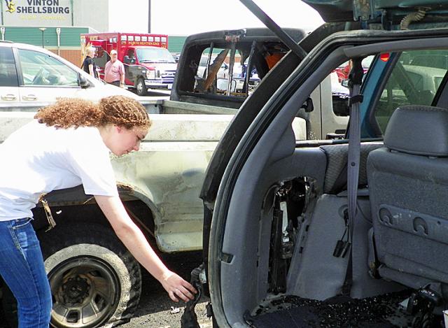 Willow Huber inspects damage to her vehicle after the 6-vehicle fire Tuesday at VSHS.