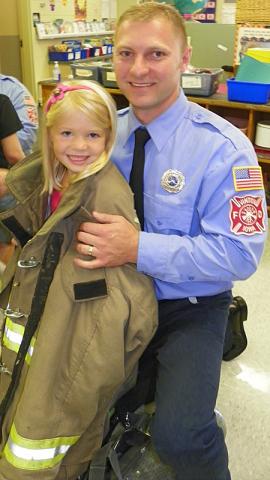Firemen Luke Henkle helps his daughter, Carmen, put on his firemen's coat.