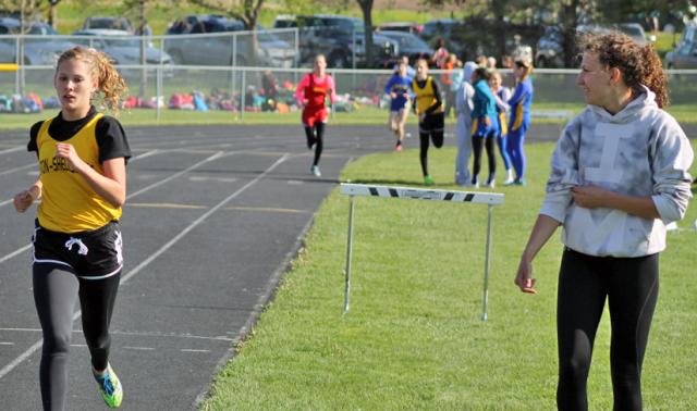 Lily Horst cheers on sister Grace as Grace leads the 1500M; Grace broke Lily's record last week.