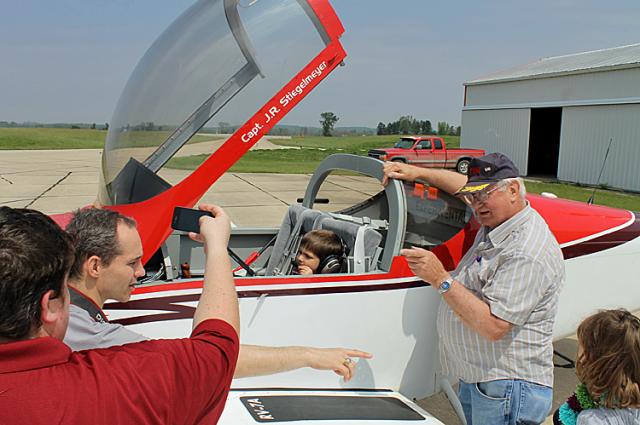 Aaron Stadelmann's parents take his photo with pilot John Steigelmeyer Saturday at the airport.