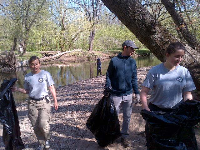 Corps members Amanda Creasia and Meghan Shoop walk along the bank with Henry Stroud.