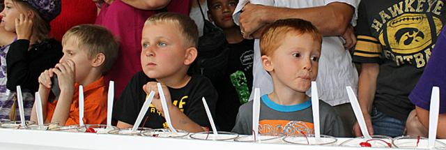 Children watch as volunteers make a long banana split.