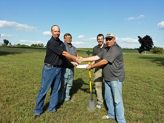 Tom Stueck of Cargill hands Bill Keller a $5K check while Ikes Bob Birker & Rick Jeray break ground.