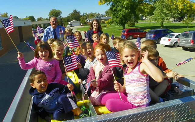 Kindergarten students wave to the camera before their ride begins.