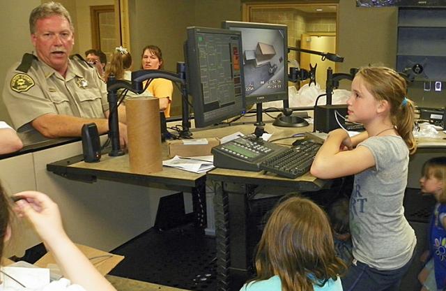 Libby Timmerman listens as Sheriff Forsyth explains how elevated tables allow dispatchers to stand.