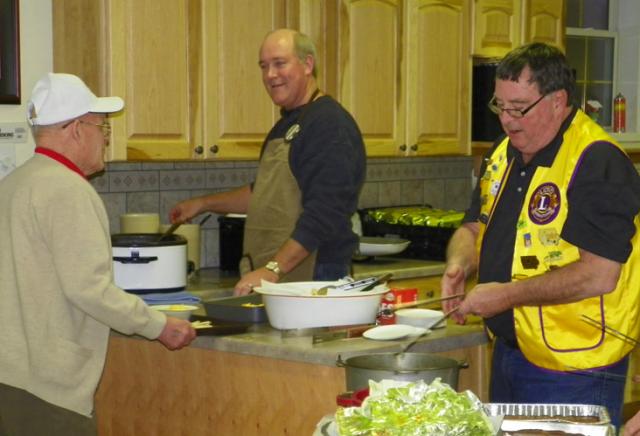 Lions Mike Barron and Dr. Alan Woodhouse serve Honor Flight veteran David Schirm at chili supper.