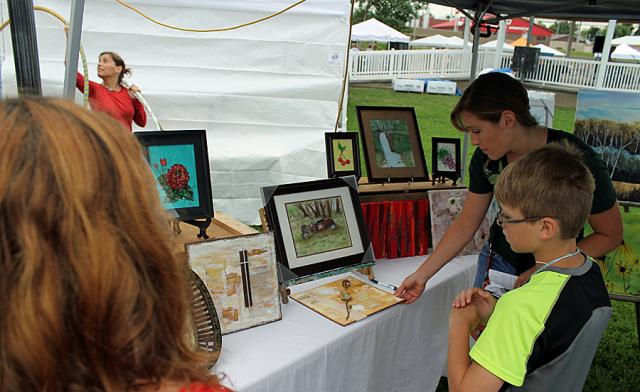Lora Walker discusses her art work with Becky Sturtz during Arts in the Park.