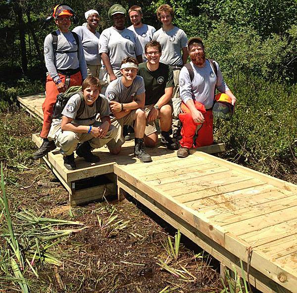 Maple 4 poses on the 422ft boardwalk they helped build on the High County Pathway.