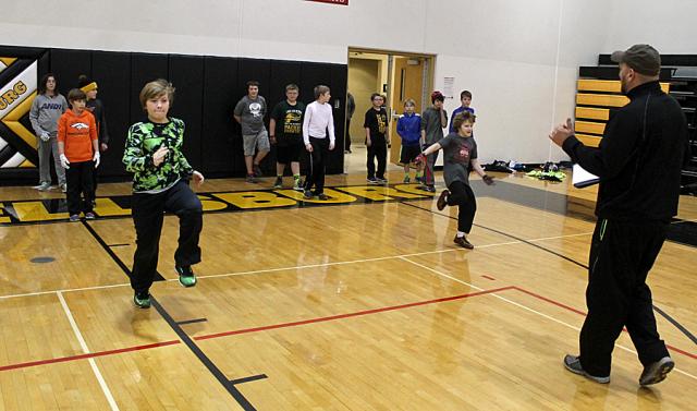 Coach Andy May leads stretching drills during the first 7-on-7 league practice.