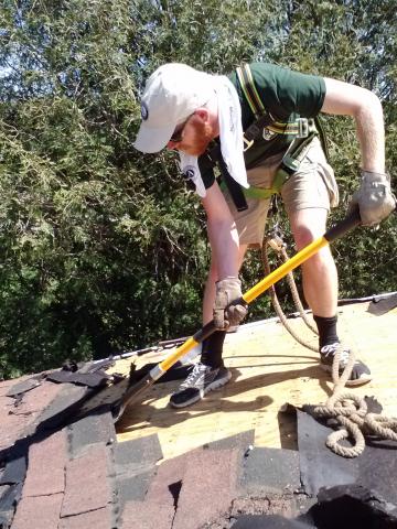 Rusty Graham tears shingles off the bath house roof at Grant River Recreation Center in Potosi, WI.