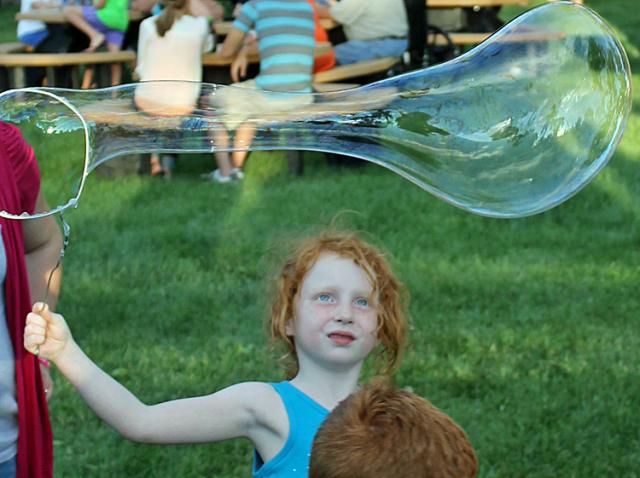 Children make bubbles during Party in the Park Friday evening.