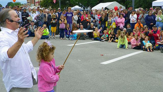 Olivia Spencer balances a plate with juggler Dean Franzen as the audience applauds.