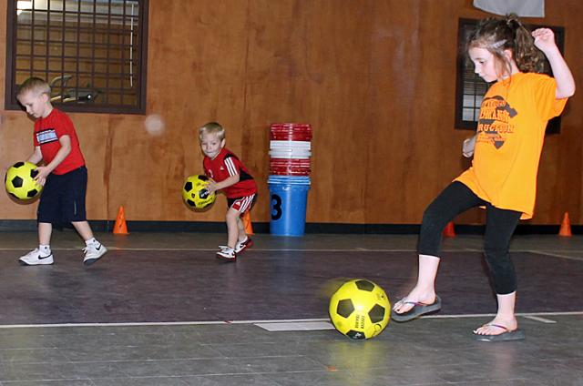 Cash Peterson and Jade Pohlmann learn how to kick soccer ball to the goal.