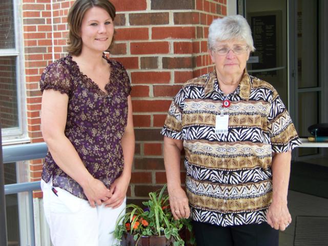 Jessica Birker and Mary Simnacher stand by the plant donated in honor of Mary upon her retirement.