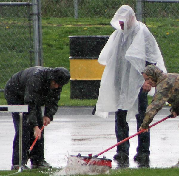 Coaches and volunteers removed water from the track before the co-ed District track meet.