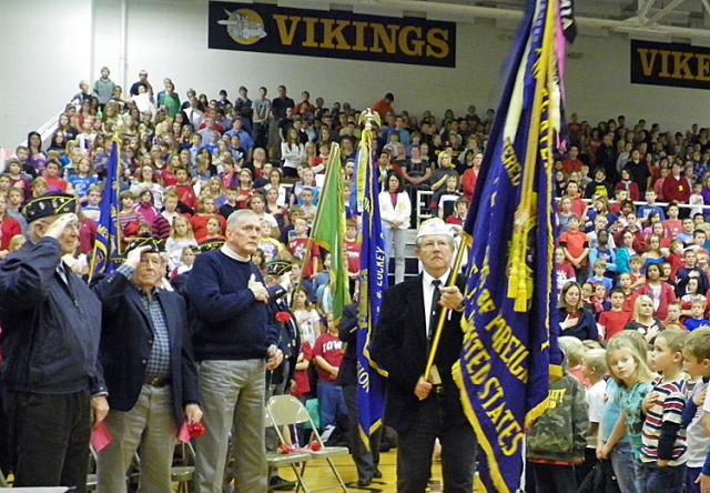 Vets and students honor the flag as the color guard retires the colors at the end of the ceremony.