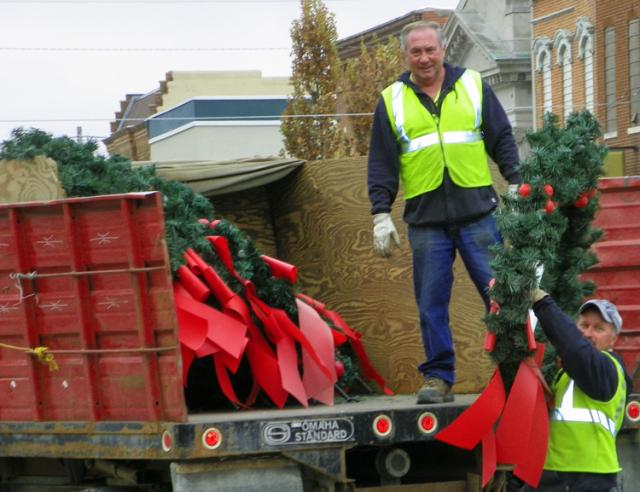 It's beginning to look a lot like Christmas: City workers put up wreaths on Monday.